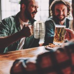 Cheerful friends toasting with drinks while spending time at pub